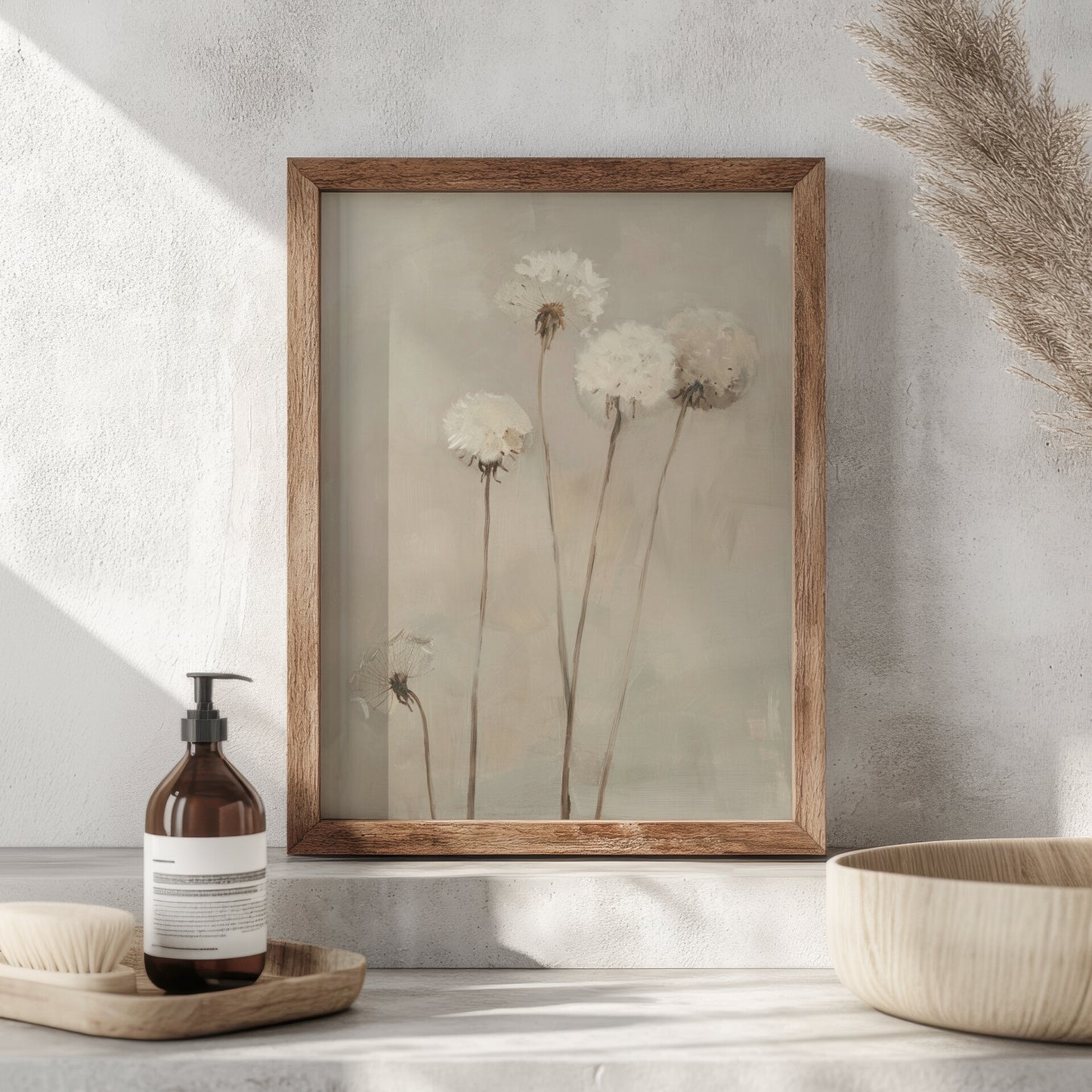 Framed artwork of flowers on a wall with a bottle and bowl on a surface below.