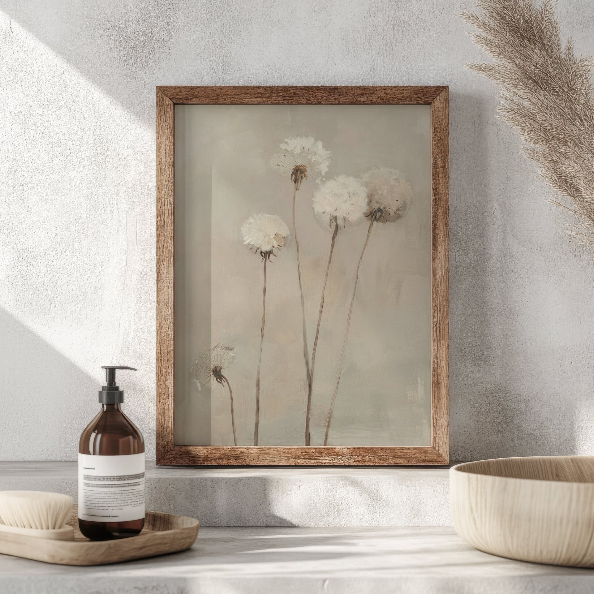 Framed artwork of flowers on a wall with a bottle and bowl on a surface below.