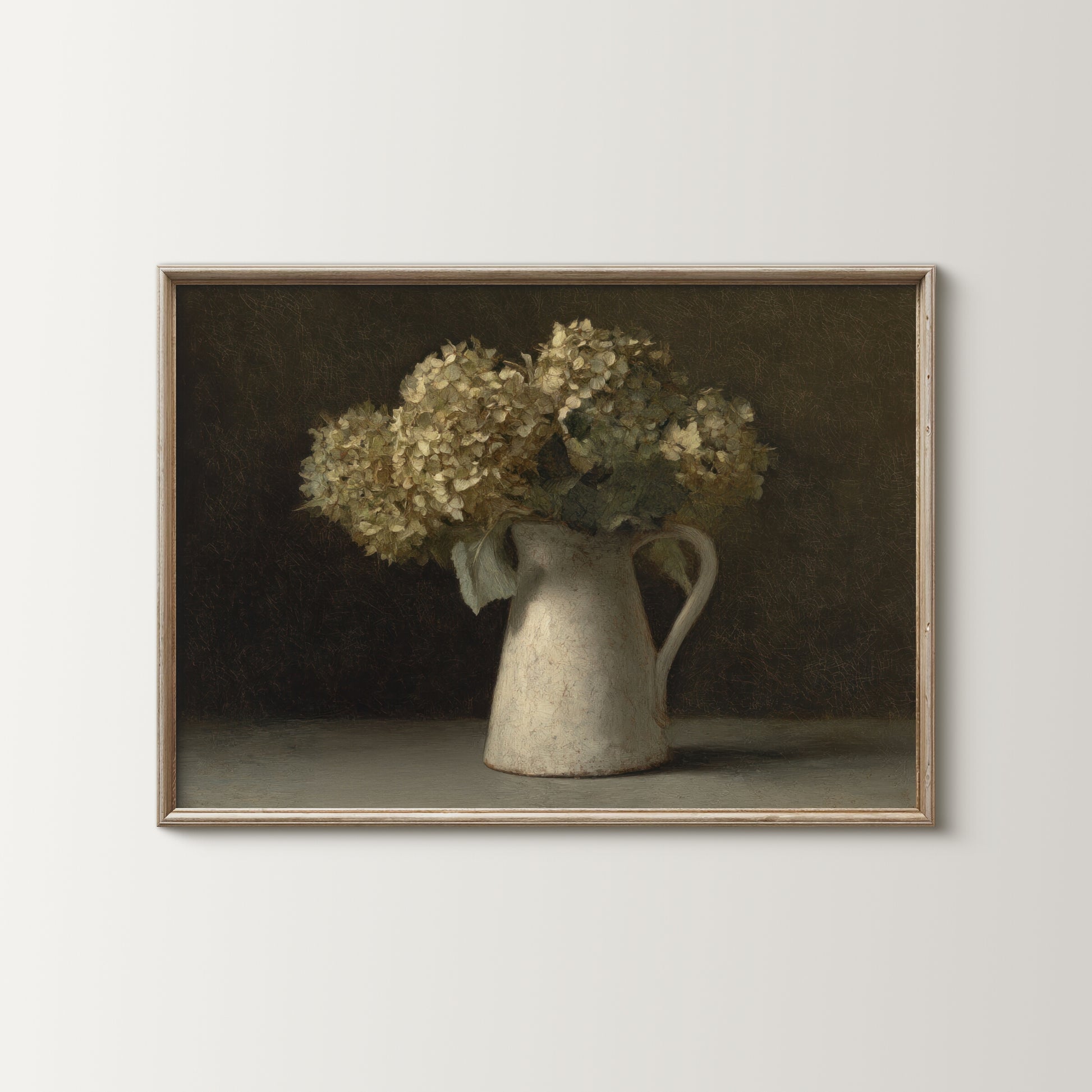 Framed artwork of a still life with flowers in a pitcher on a plain wall.