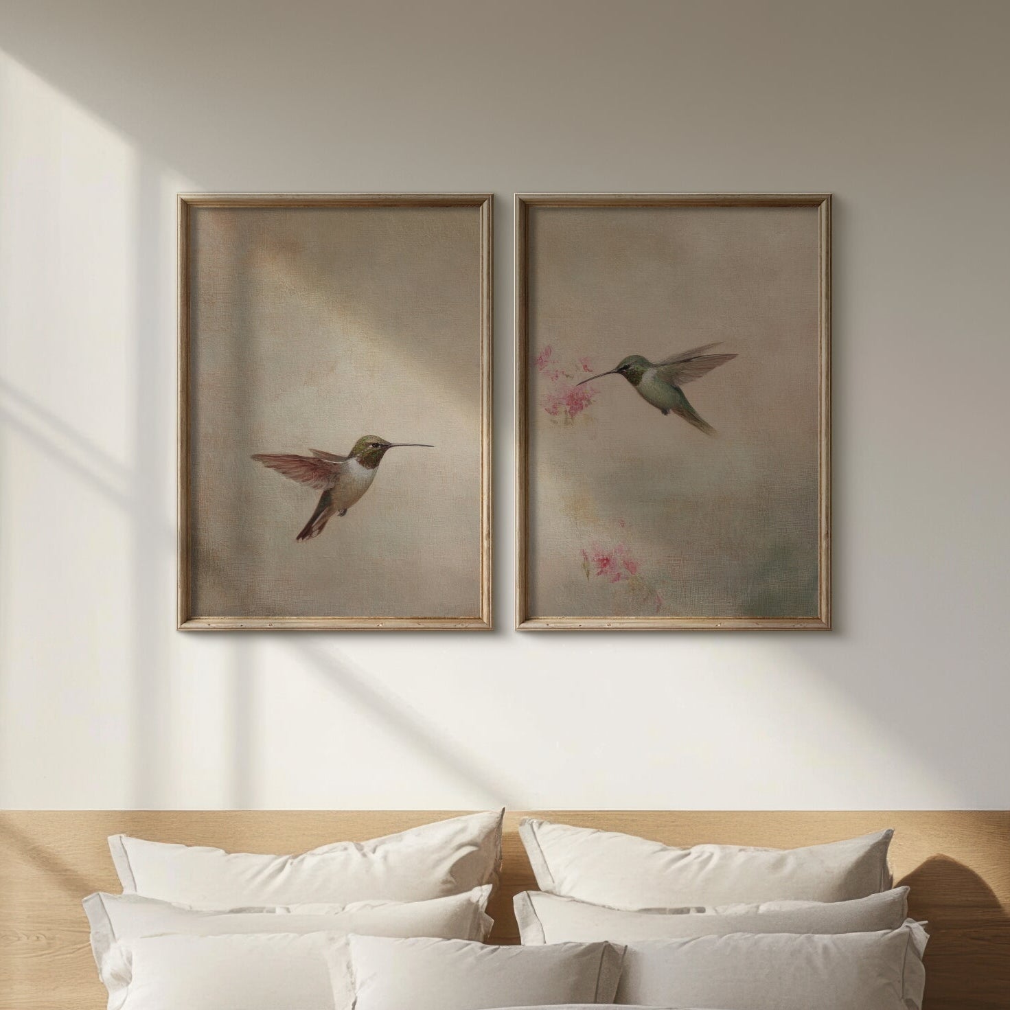 Two framed paintings of hummingbirds on a wall above a bed.