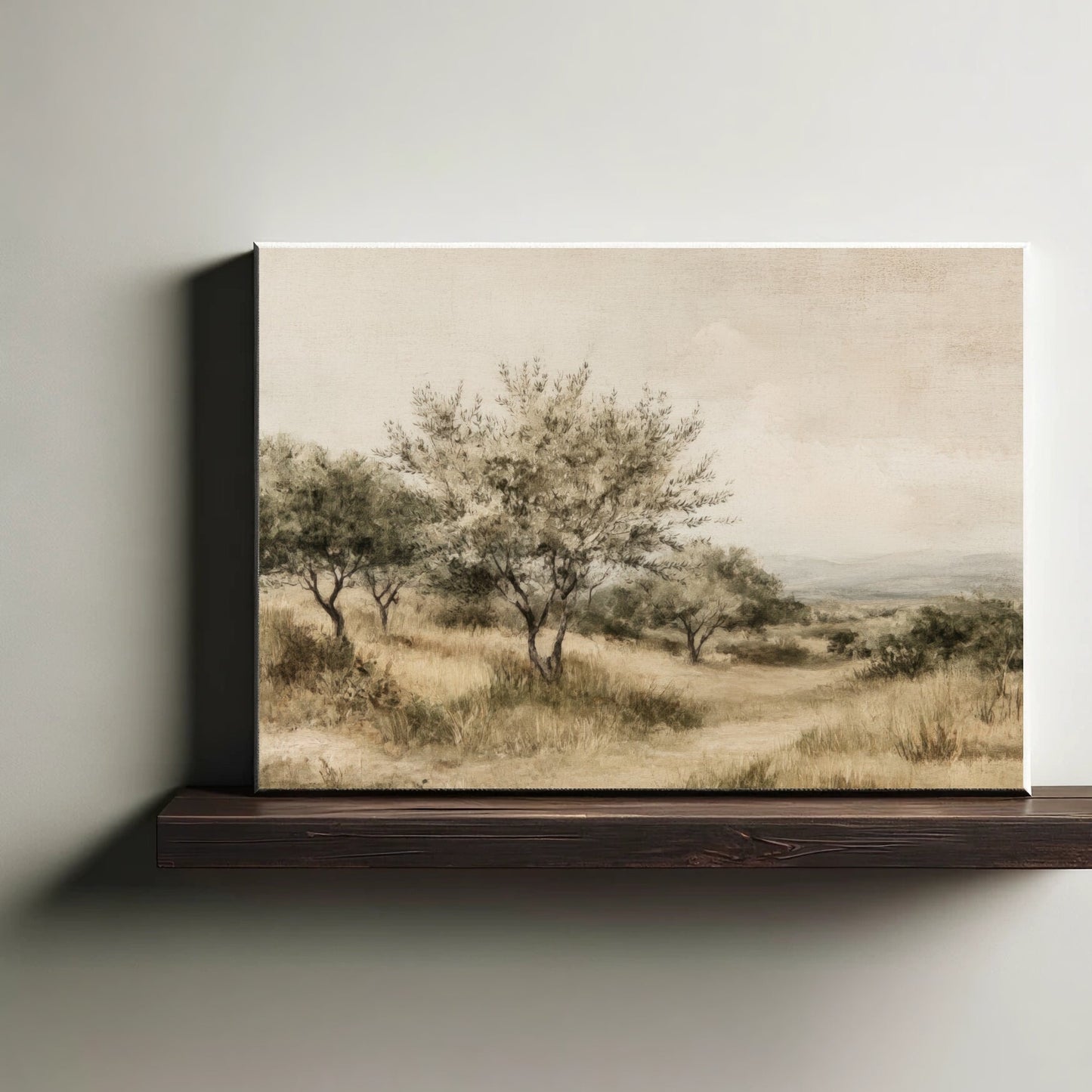 Canvas print of a landscape with trees and grass on a wooden shelf against a plain wall.