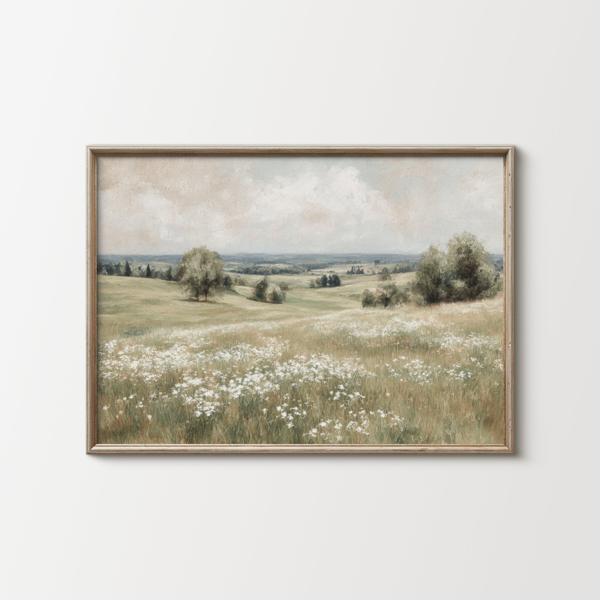 Framed artwork of a landscape with a field and trees on a white wall