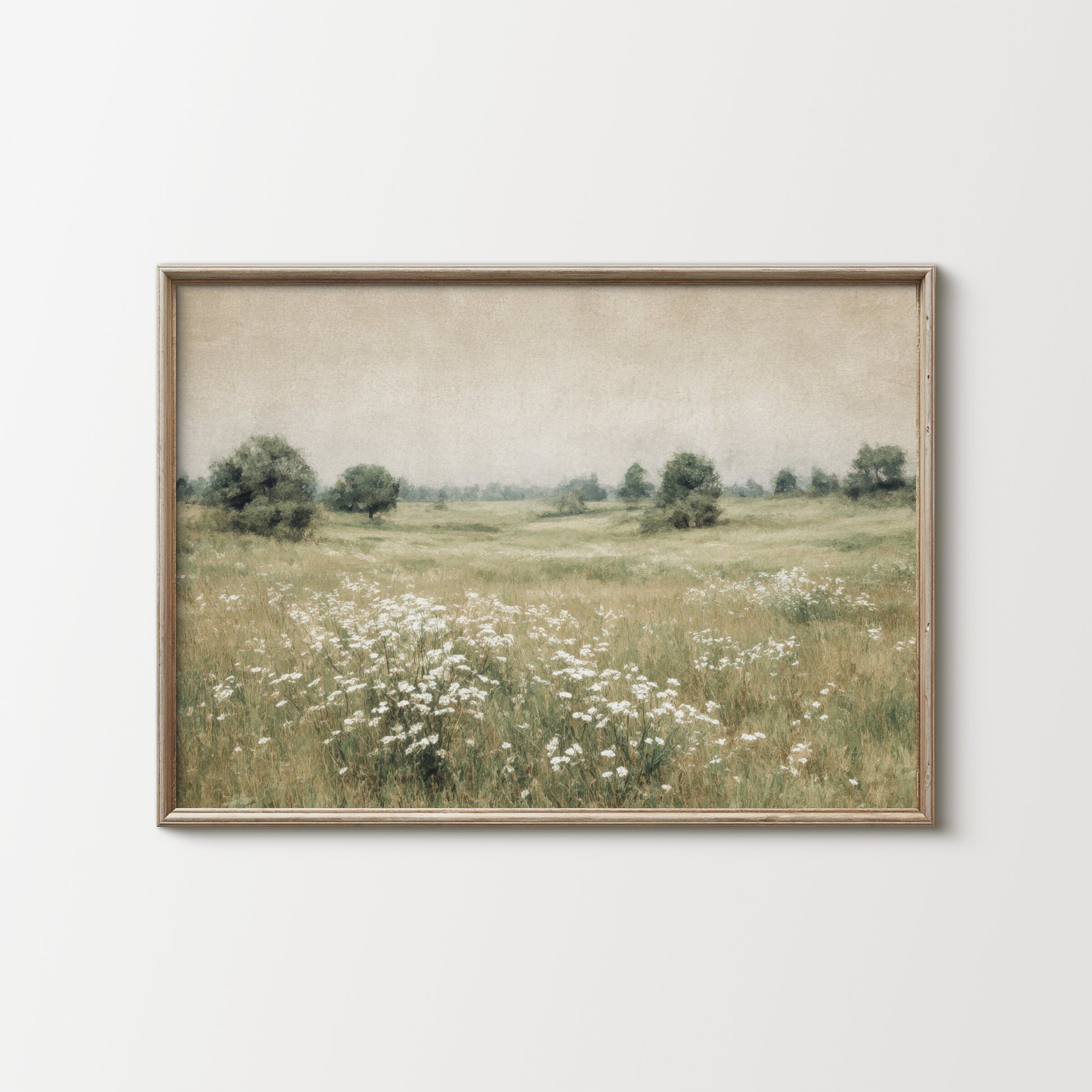 Framed artwork of a landscape with a field and trees on a white wall