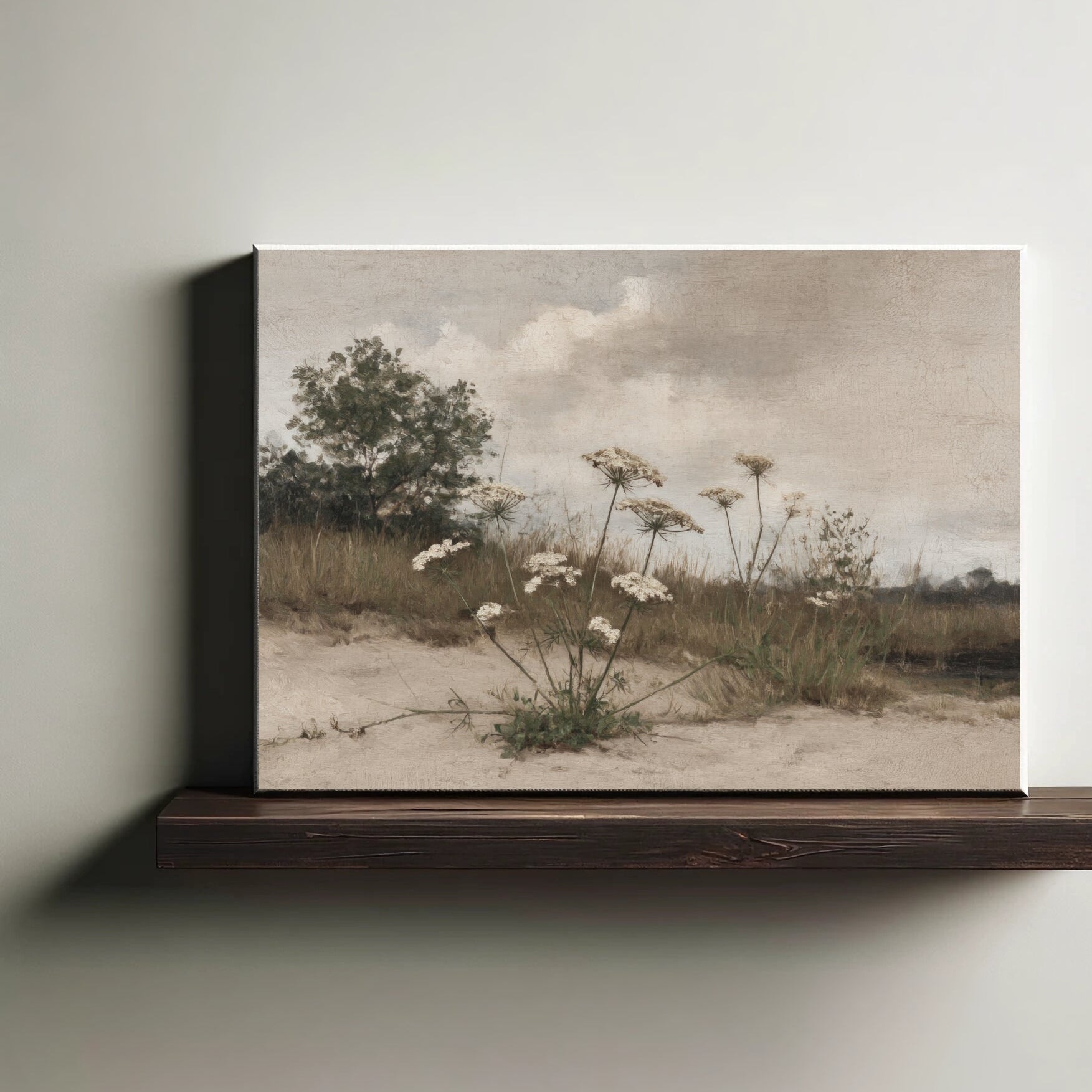 Framed artwork of a landscape with flowers and trees on a wooden shelf.
