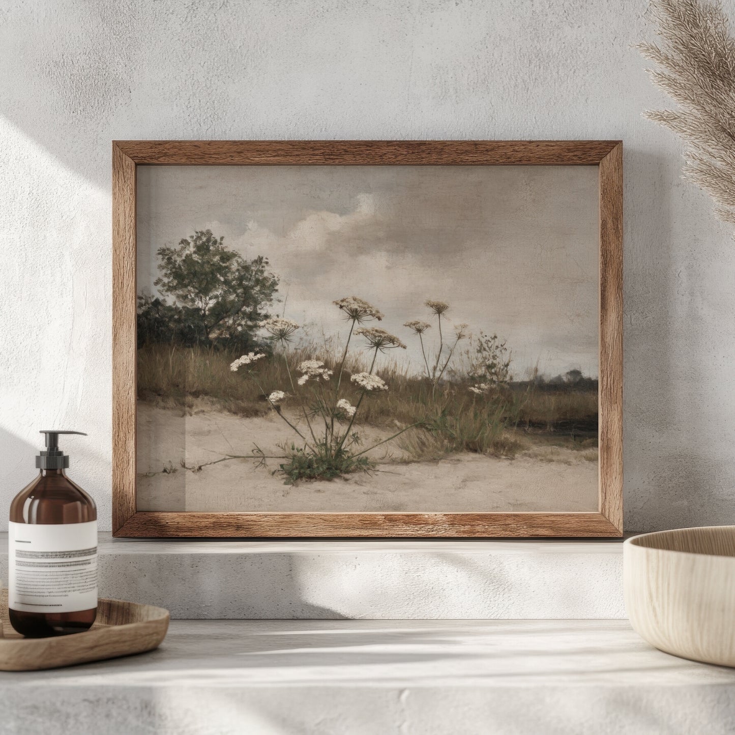 Framed landscape print of a field with flowers on a wall above a shelf.
