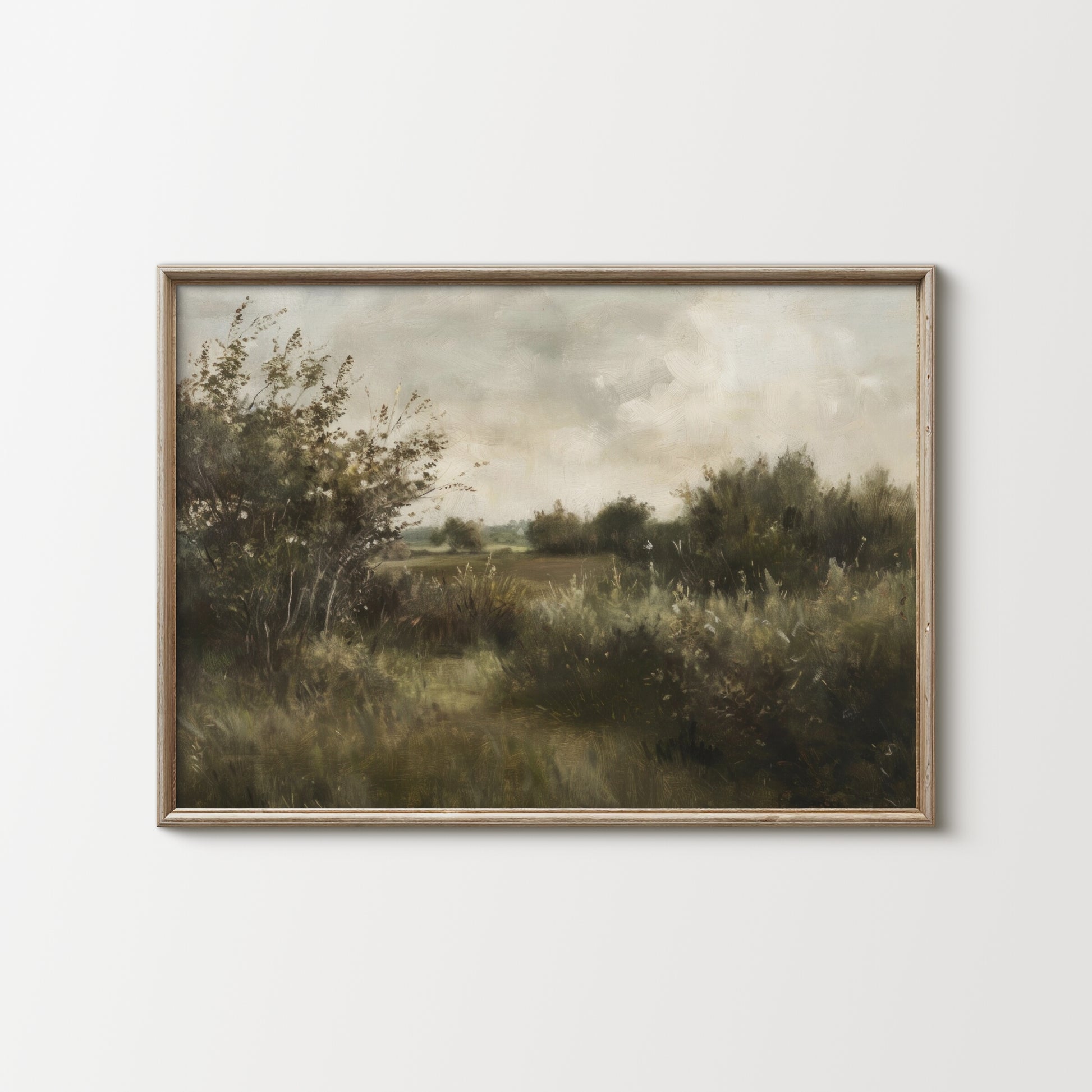Framed painting of a landscape with trees and fields on a white wall