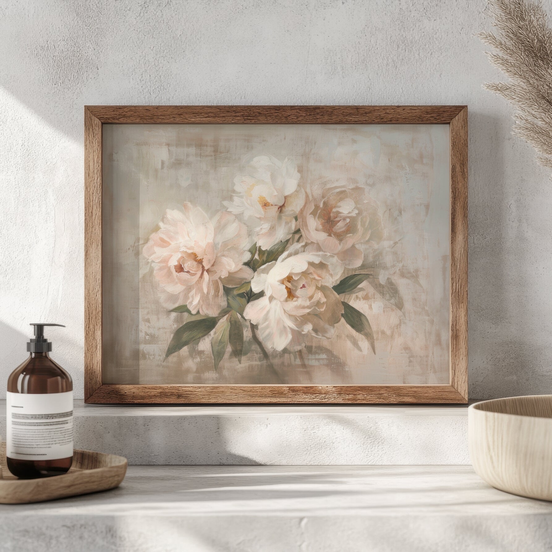 Framed floral painting on a wall with a bottle and bowl in the foreground.