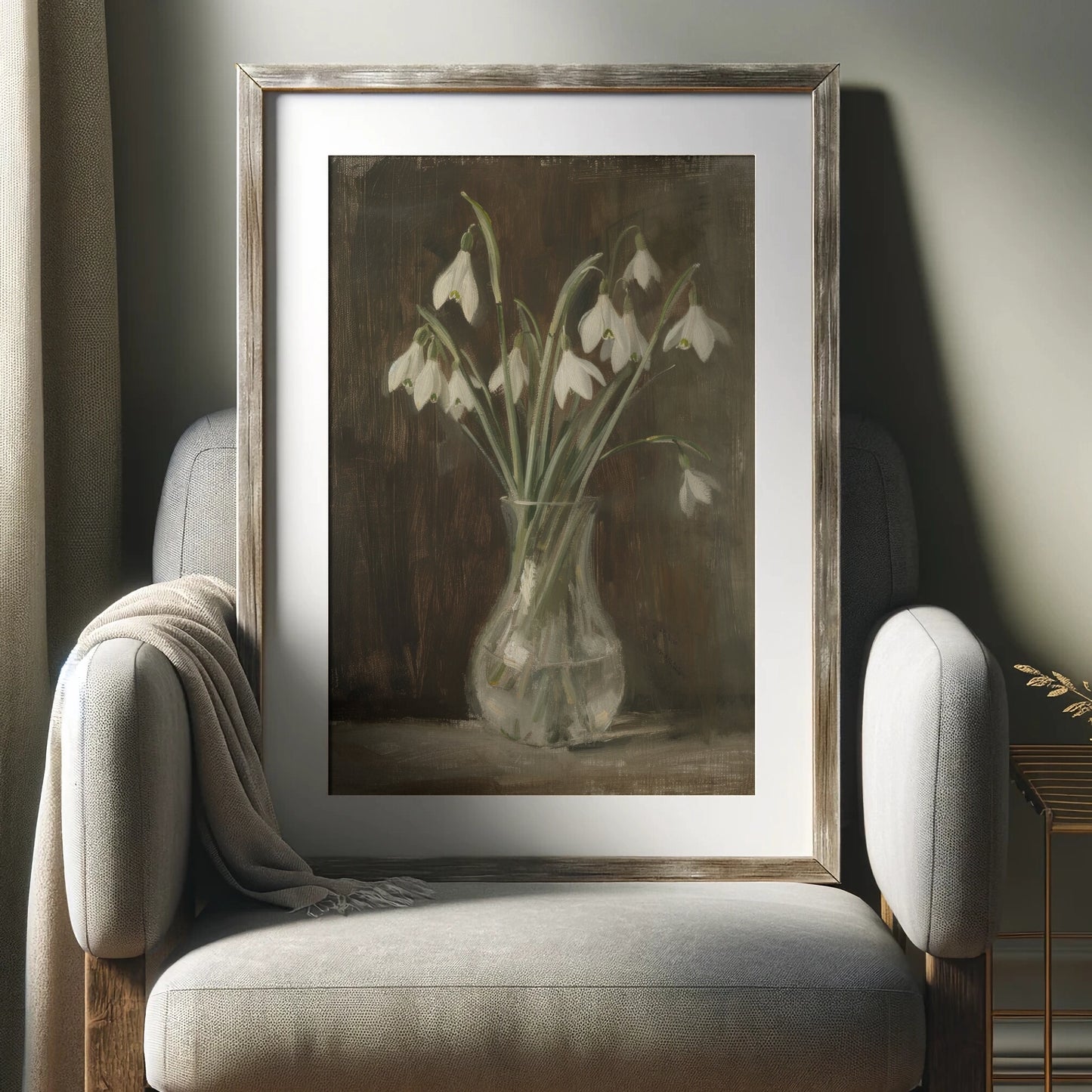 Framed artwork of snowdrops in a vase on a gray armchair.