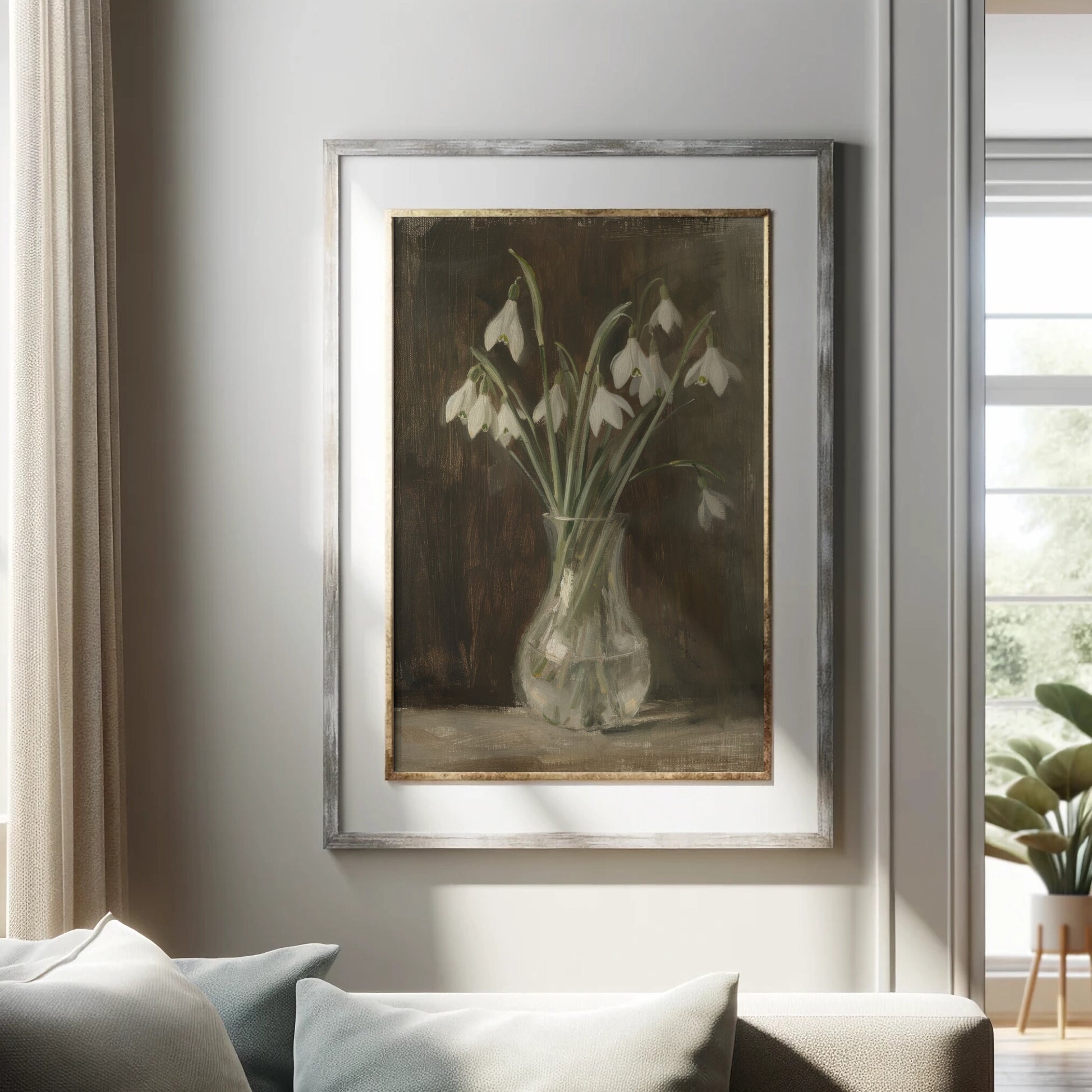 Framed artwork of snowdrops in a vase on a wall above a sofa.