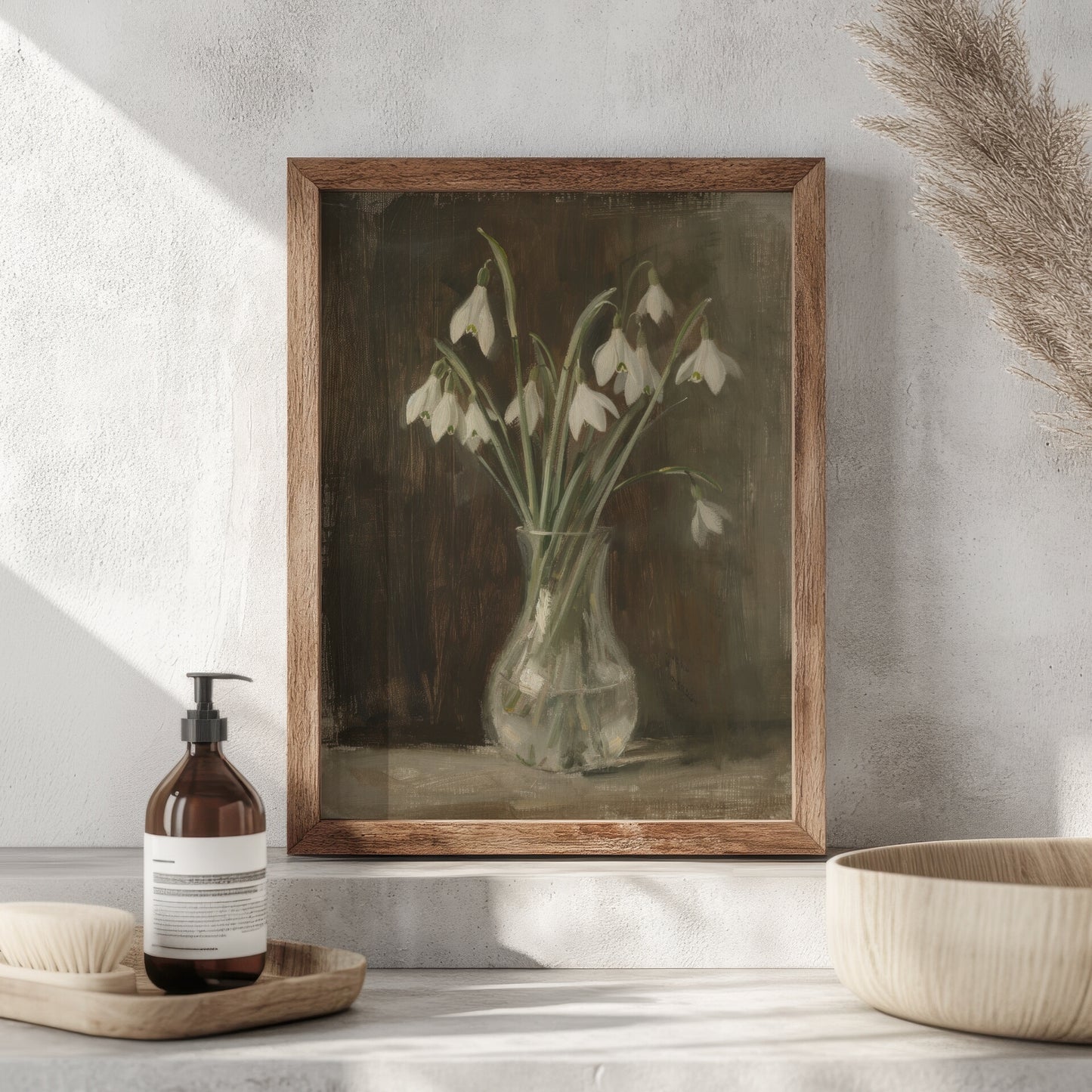 Framed botanical print of snowdrops on a neutral wall with decorative items below.
