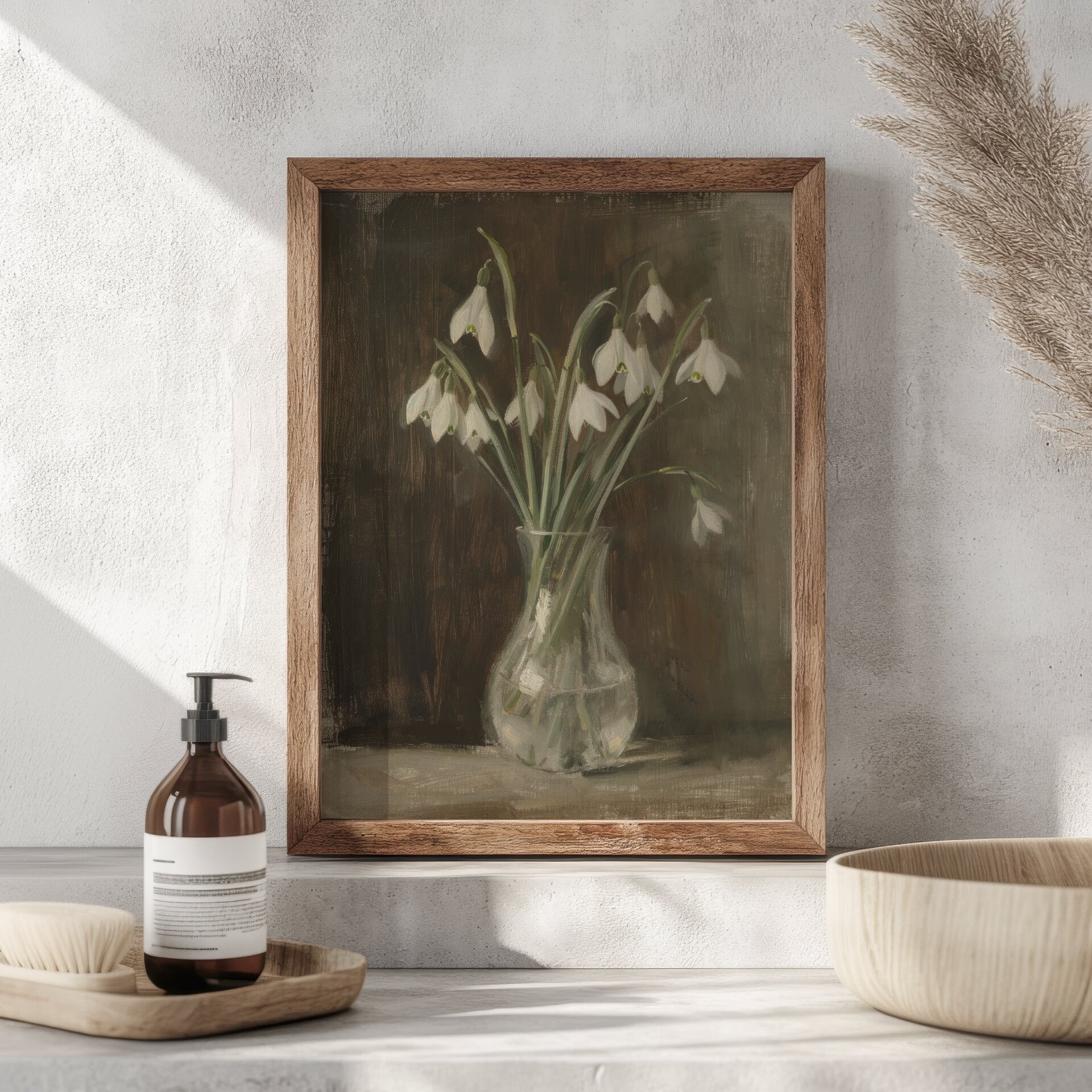 Framed botanical print of snowdrops on a neutral wall with decorative items below.