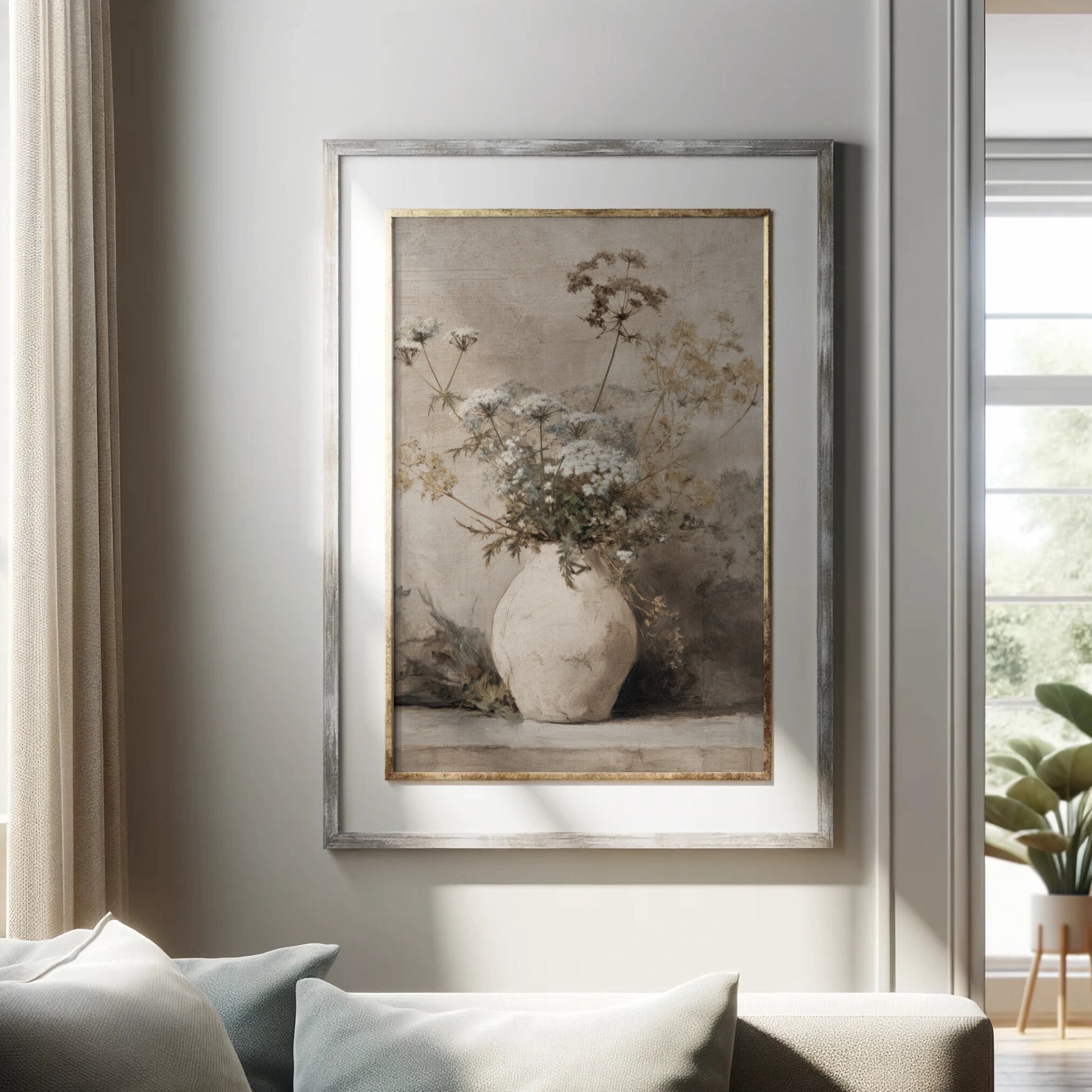 Framed artwork of a vase with flowers on a wall in a room with a couch and plant.
