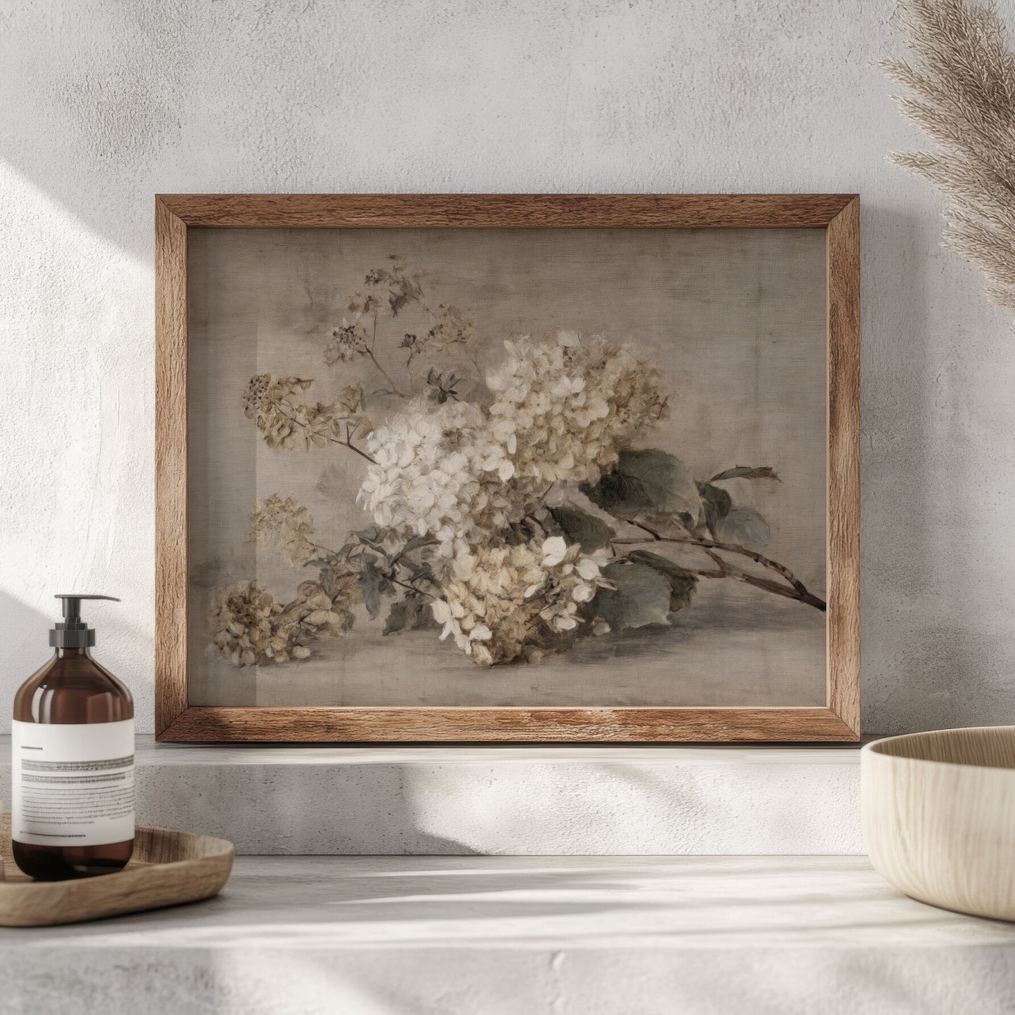 Framed floral artwork on a wall with a bottle and bowl in the foreground.