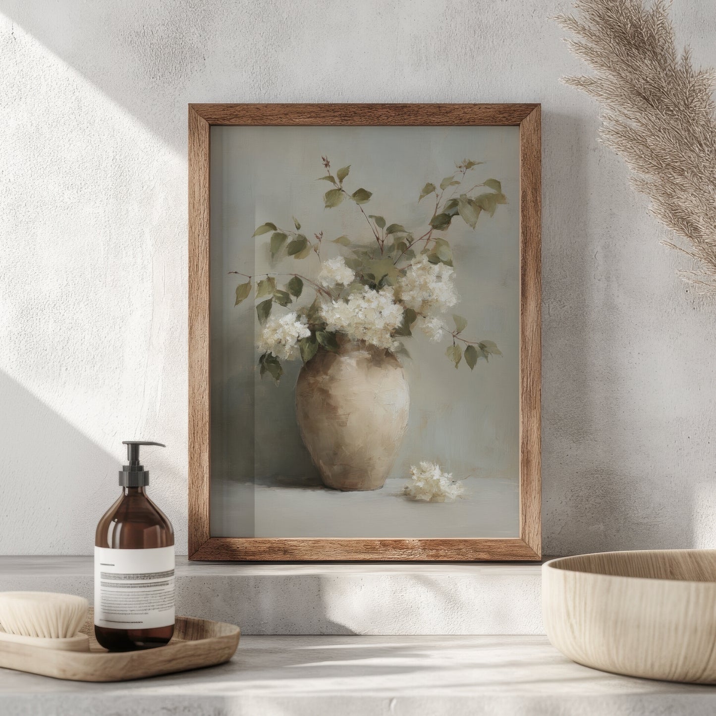 Framed artwork of a vase with flowers on a neutral surface with decorative items.