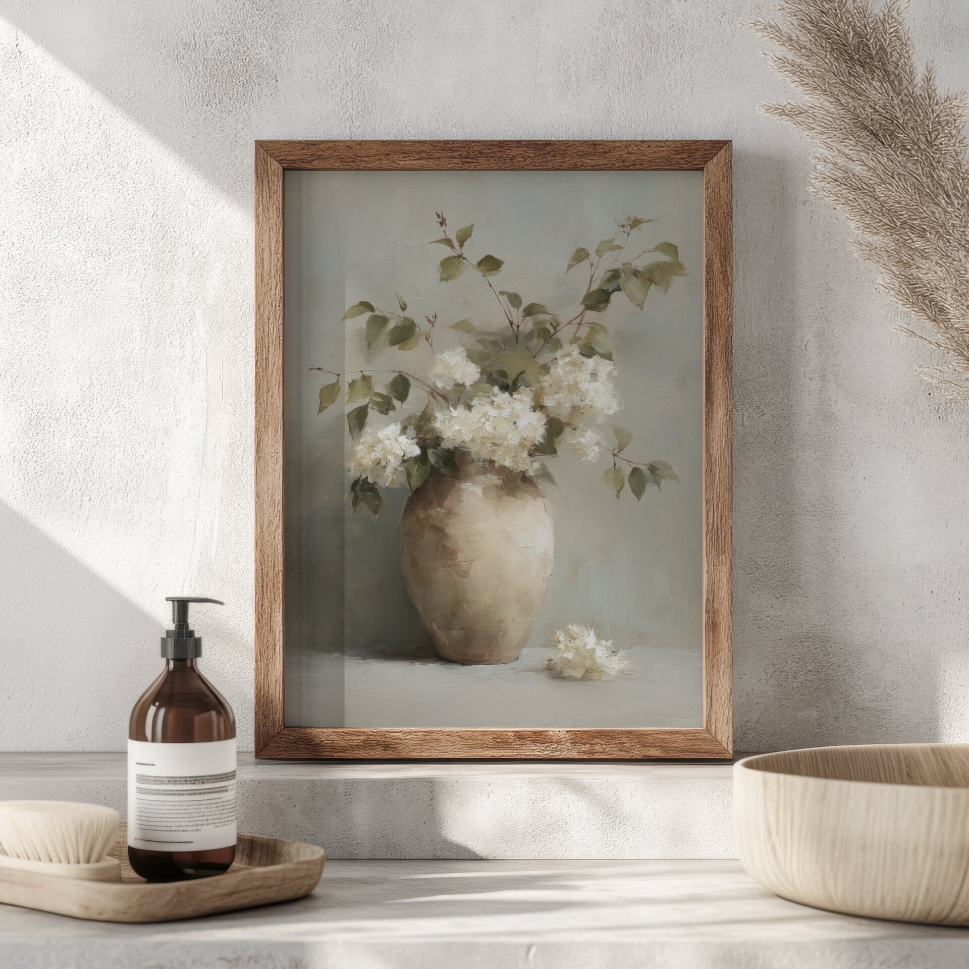 Framed artwork of a vase with flowers on a neutral surface with decorative items.
