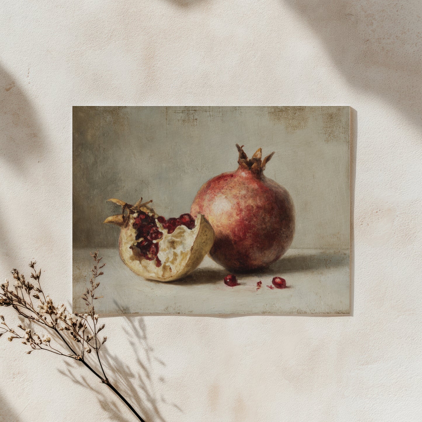 Framed still life painting of pomegranates on a textured wall.